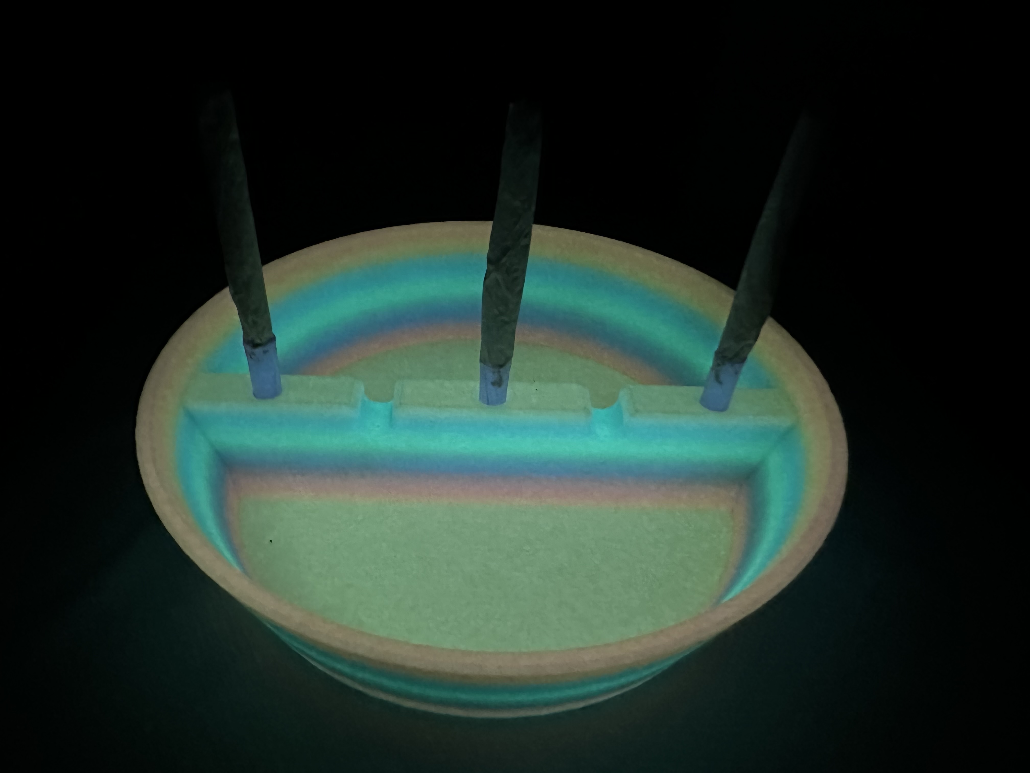 The same ash tray glowing teal and green in the dark